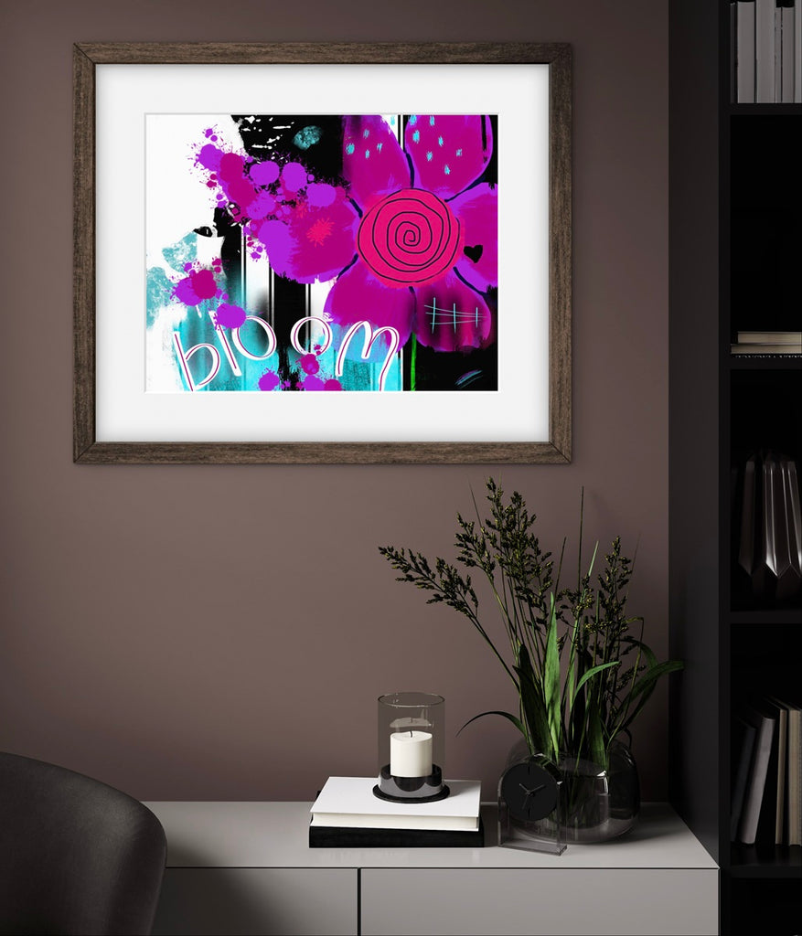 Framed artwork with colorful flowers and the word 'bloom' on a wall in a room.