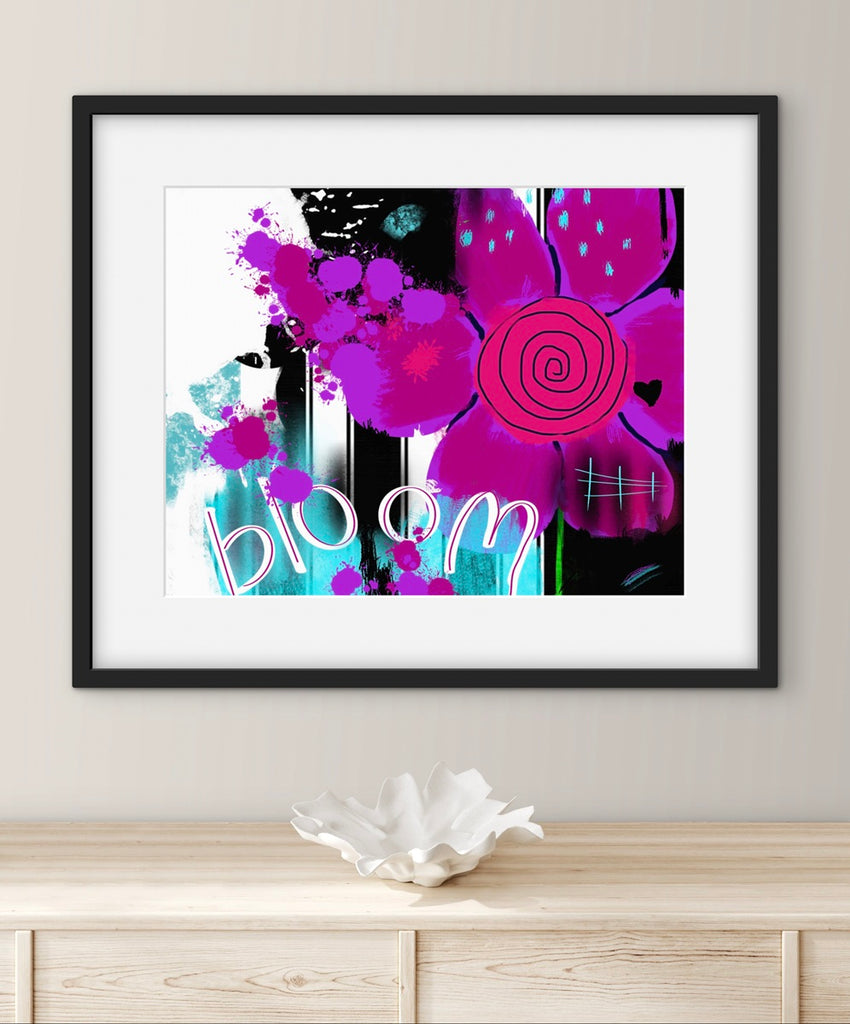 Framed abstract artwork with pink flowers and text on a wall above a wooden cabinet.