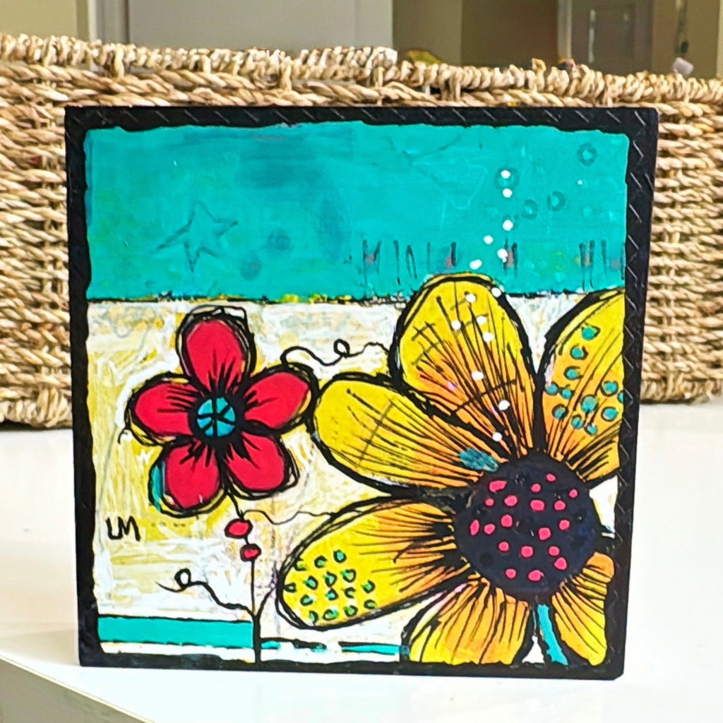 flower painting standing on a table in front of a basket