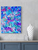 Abstract colorful painting on a wall above a cabinet with decorative items.