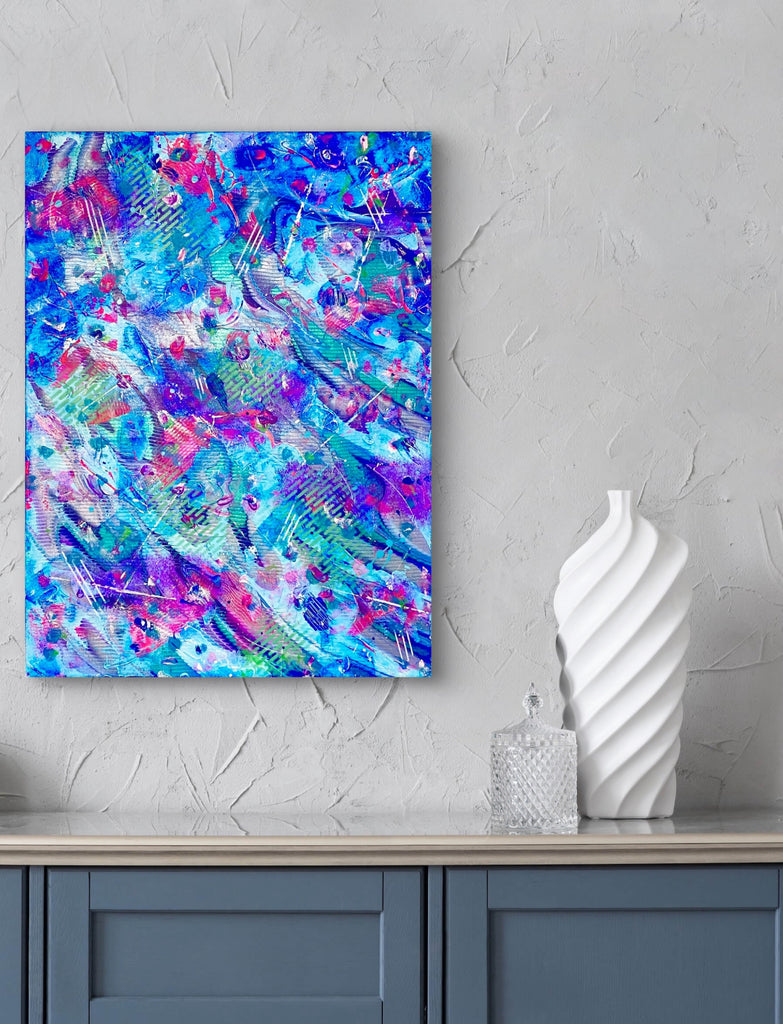 Abstract colorful painting on a wall above a cabinet with decorative items.