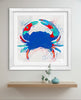 Framed abstract crab art print on a wall above a wooden shelf.