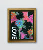 Framed artwork with colorful flowers and the word 'LOVE' on a black background.