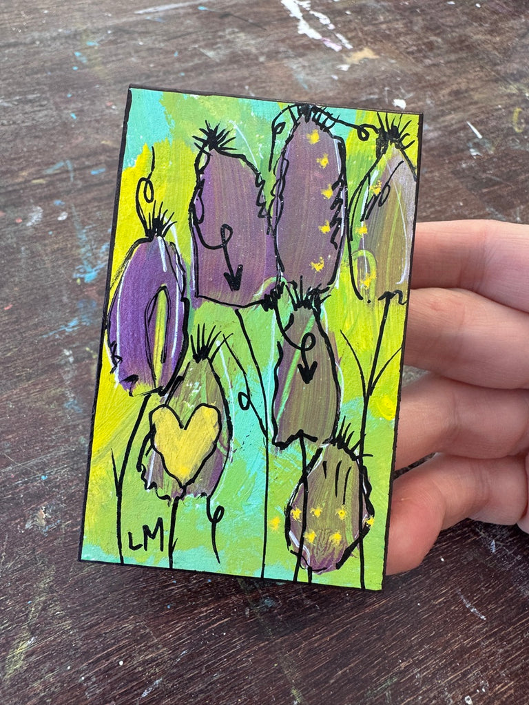 small painting being held by a hand on a wood surface