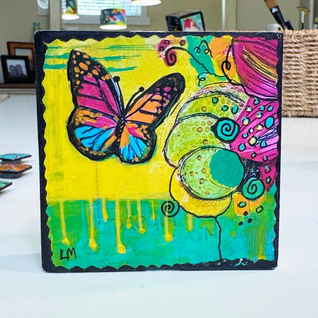 butterfly painting on a wood block standing on a white table 