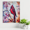 Canvas print of a red cardinal bird on a branch with flowers, placed on a white surface with plants.