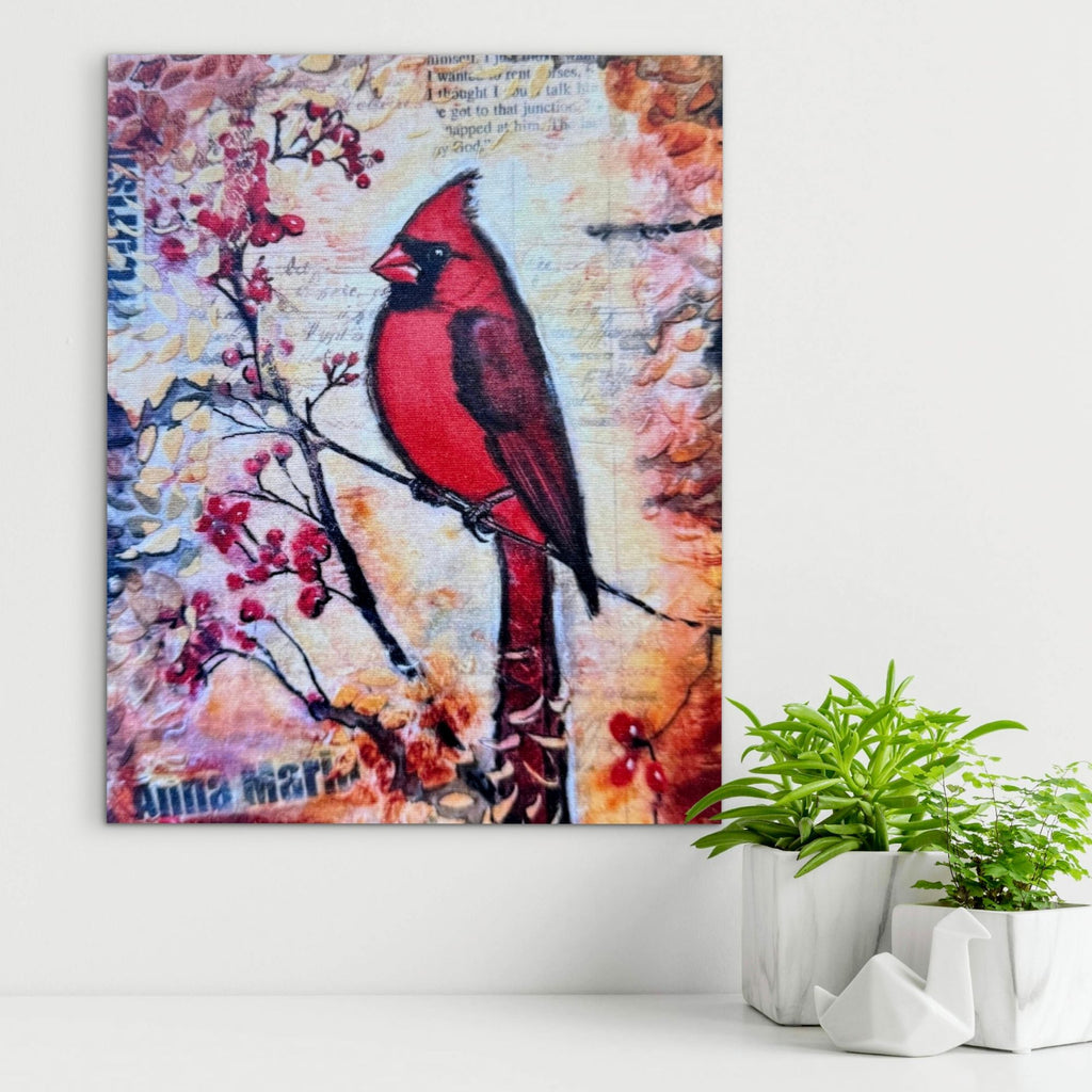 Canvas print of a red cardinal bird on a branch with flowers, placed on a white surface with plants.