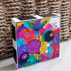 Angled view of Cheer Up floral art block showing its colorful abstract flowers and black-and-white painted top and side edges.