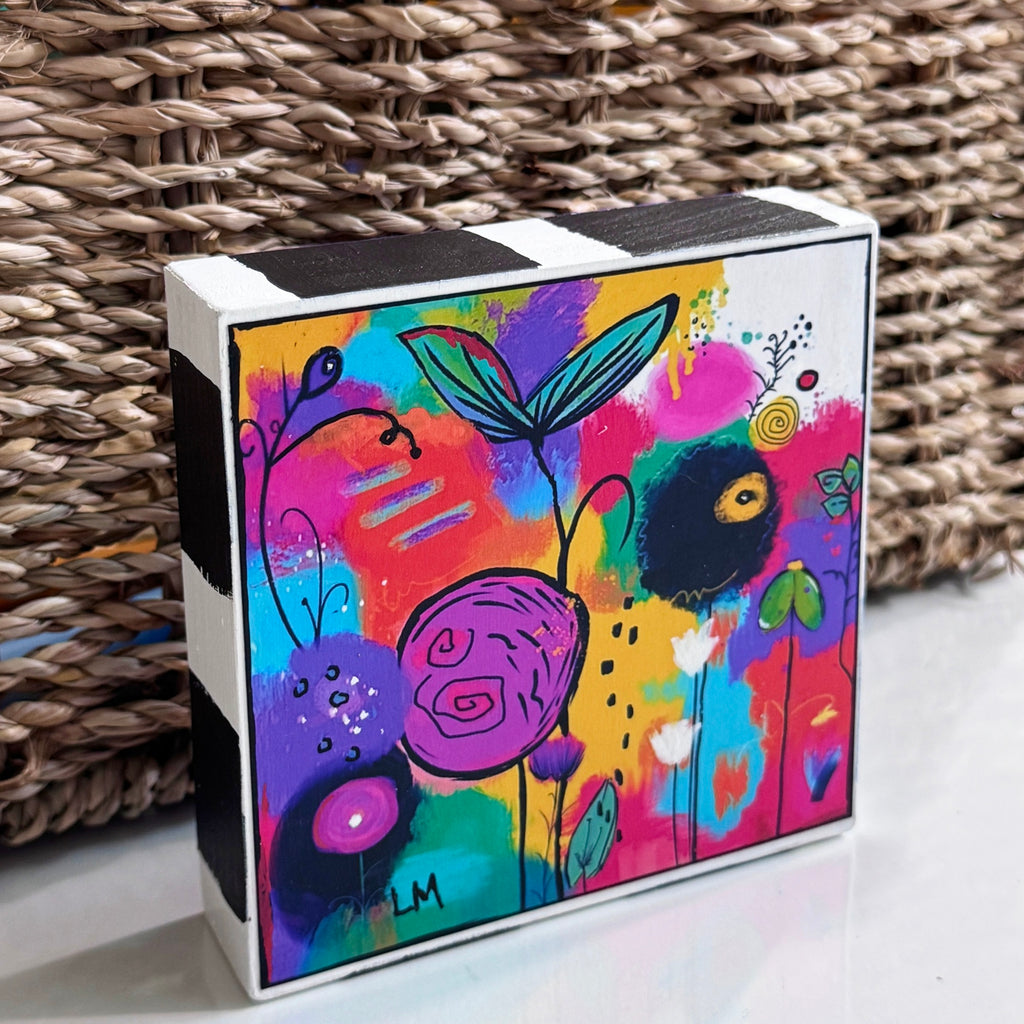 Angled view of Cheer Up floral art block showing its colorful abstract flowers and black-and-white painted top and side edges.