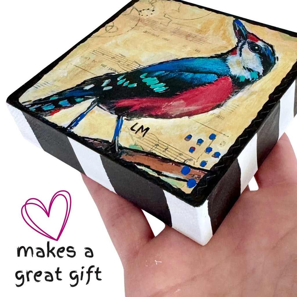 a hand holding up a bird art block painting  with a white background and the text makes a great gift'