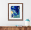 Framed abstract art piece on a wall with a wooden shelf and decorative items.