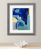 Framed abstract art print with blue and yellow colors on a white wall.