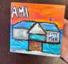 coaster with a pier and text saying "AMI City Pier" held by a hand on a table