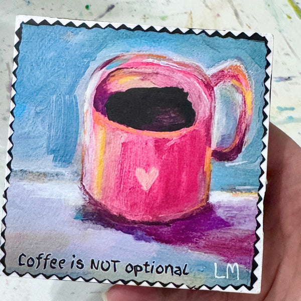 A hand holding a painting of a cup of coffee with text "Coffee is not Optional" and the artist initials 'LM'