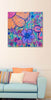 Colorful floral painting on a wall above a light blue sofa with patterned cushions.