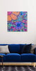 Colorful abstract painting on a wall above a blue sofa with patterned cushions.