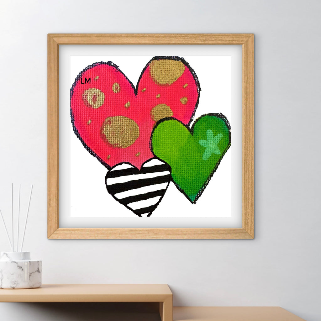Framed artwork with colorful hearts on a white wall.