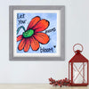 Framed artwork with a red flower and motivational quote on a white wall, accompanied by a red lantern and decorative branches.