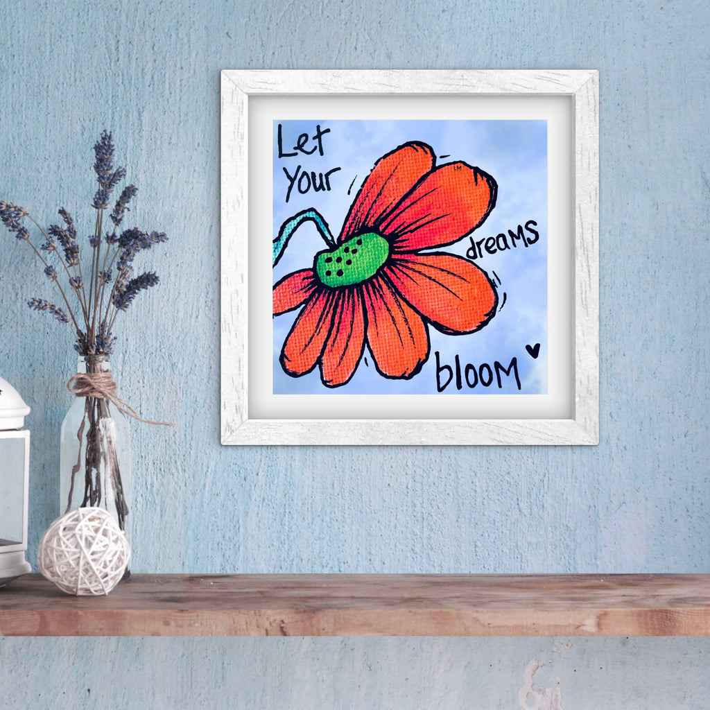Framed artwork with a red flower and motivational quote on a blue wall.