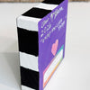 sides of a wood block painted black and white with the back purple showing artist signature