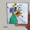 a hand holding a block with colorful floral art on it