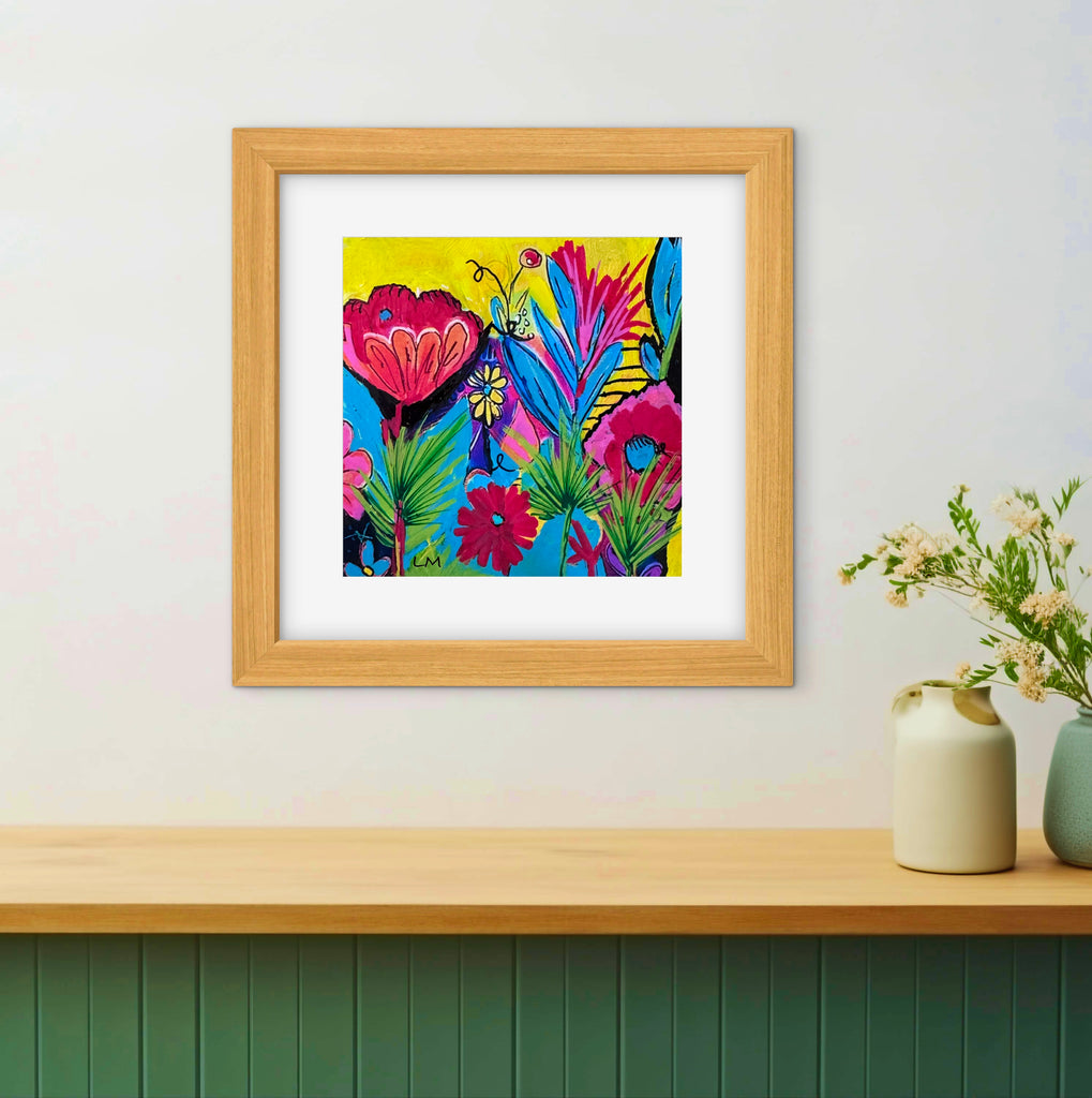 Colorful flower artwork in a natural wood frame on a white wall above a shelf with some vases on it