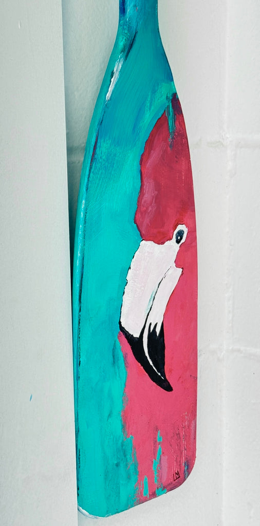 Painted oar paddle with a flamingo design on a white background