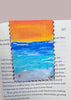 painting of a beach setting on a bookmark displayed in a book