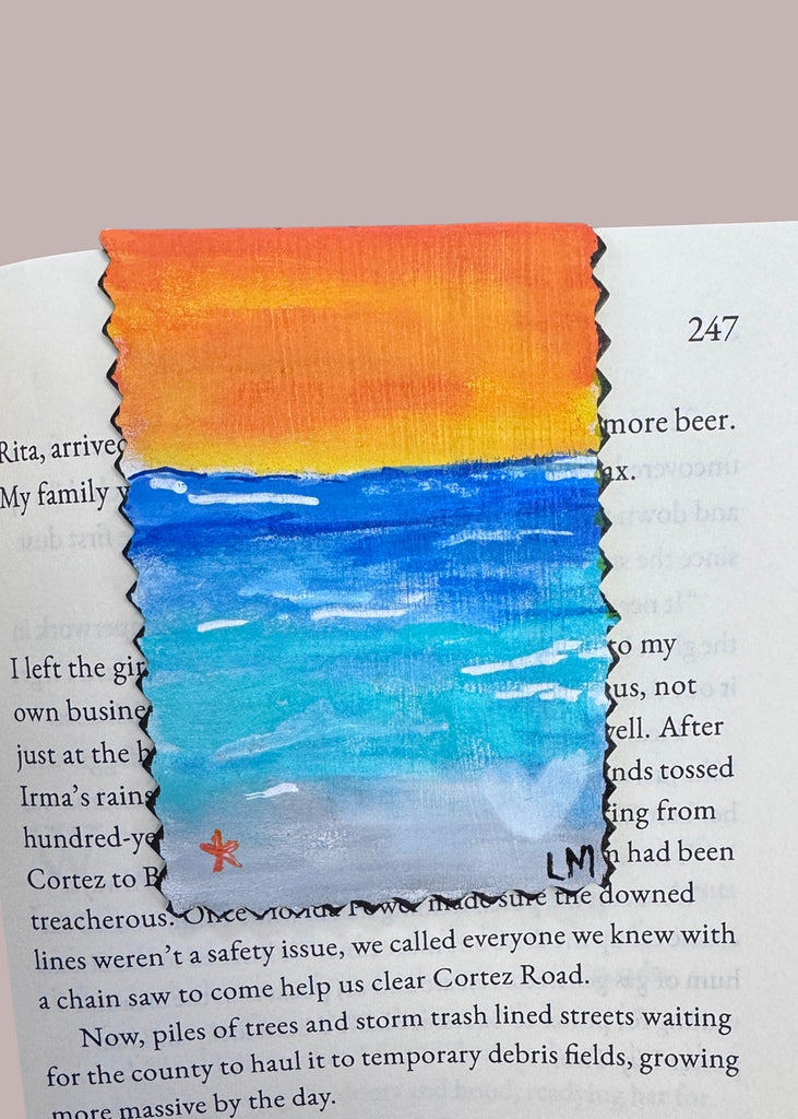 painting of a beach setting on a bookmark displayed in a book