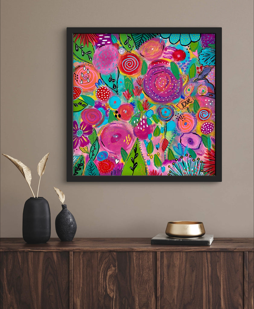 colorful floral painting in a frame above a table with vases
