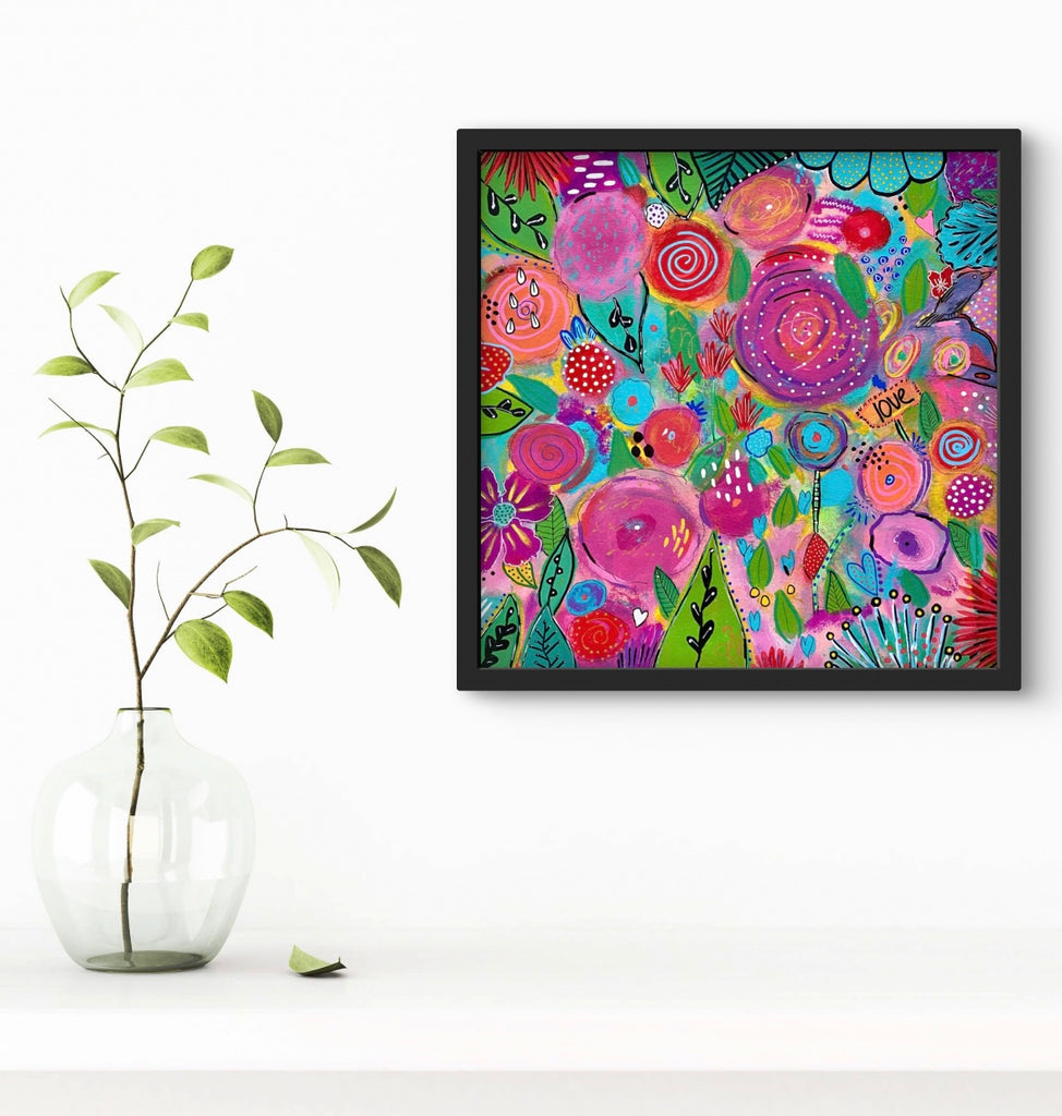 floral painting with black frame on a white wall next to a vase