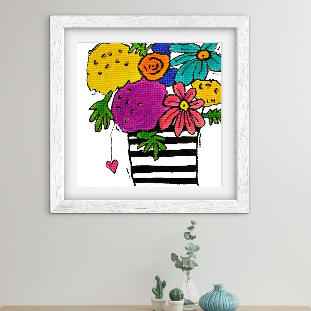 Framed colorful artwork of a striped bag with flowers on a light gray wall.
