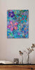 Colorful floral painting on a wall above a wooden shelf with decorative items.