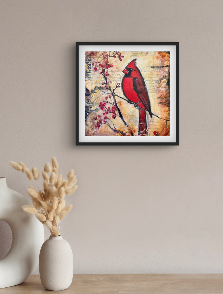 Framed artwork of a red cardinal bird on a textured background, displayed on a wall above a vase with dried plants.