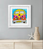 Framed artwork of a colorful van on a beach with a vase and starfish decoration below.