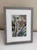 floral art print in a gray frame with a white mat sitting on a white table