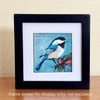Bird and Berries acrylic painting by Lori McKinnon, displayed with a white mat in a black frame on a wooden surface. Frame not included