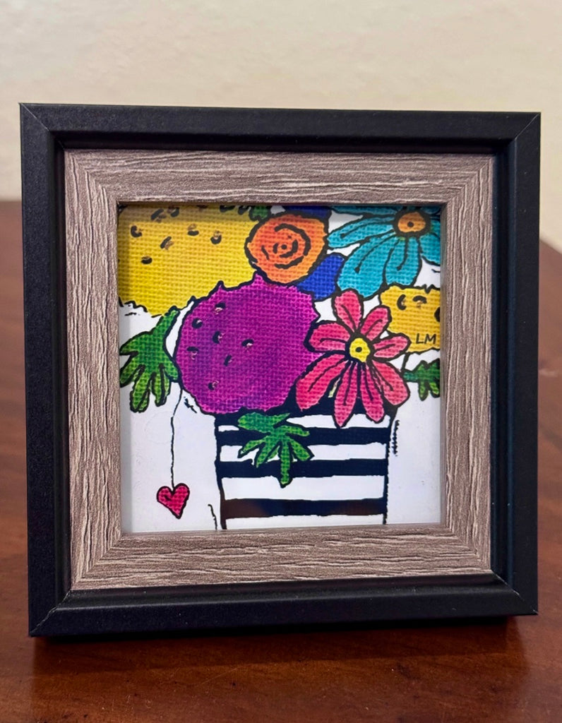 framed floral art print in a brown and black frame. Colorful flowers in a black and white striped vase