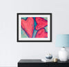 Framed abstract art print of a pink heart on a white wall above a black cabinet with decorative items.