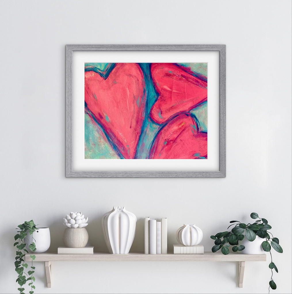 Framed abstract art with a heart design on a wall above a shelf with decorative items.