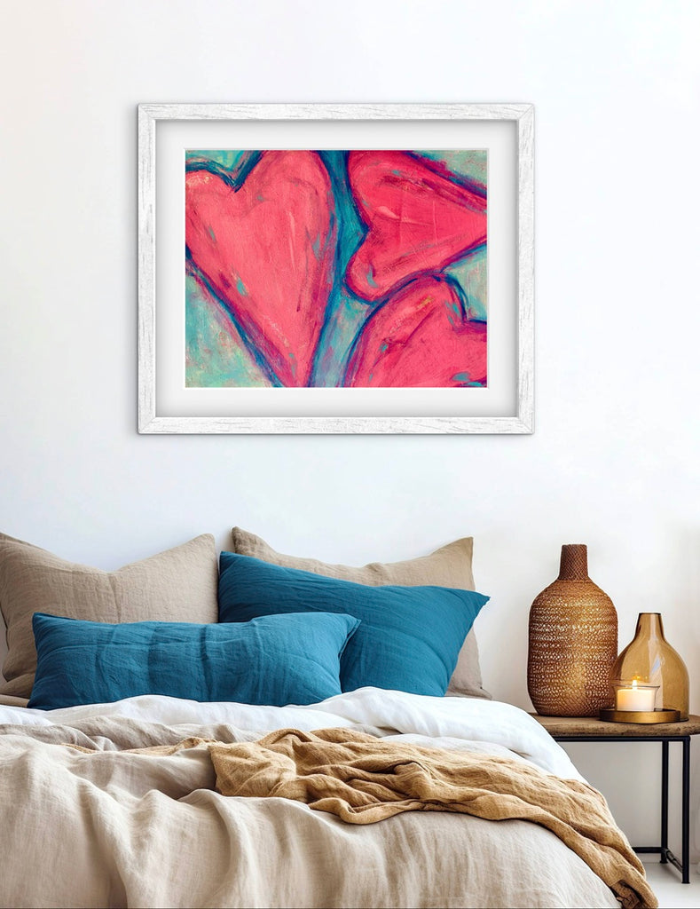 Framed abstract art above a bed with pillows and a vase.