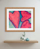 Framed abstract art with pink hearts on a wall above a shelf with decorative items.