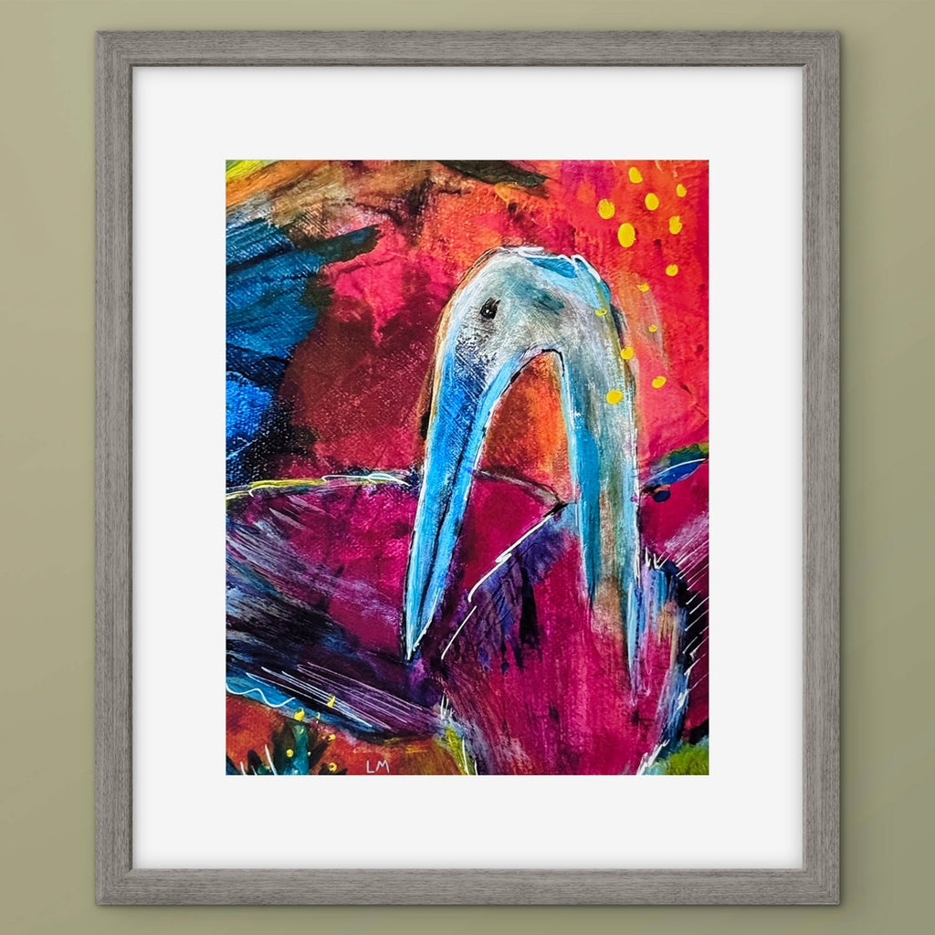 Framed abstract art print featuring a stylized heron with a long beak against a vivid red, pink, and blue background, set in a gray frame with a white mat.