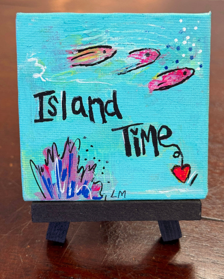 Small canvas painting with 'Island Time' text and fish displayed on a wooden stand
