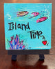 Small canvas painting with 'Island Time' text and fish displayed on a wooden stand