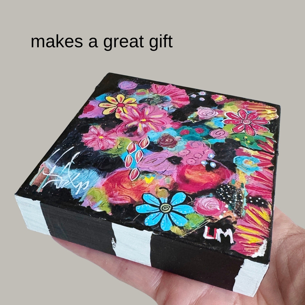 a hand holding a painted wood block with text 'makes a great gift' written above it