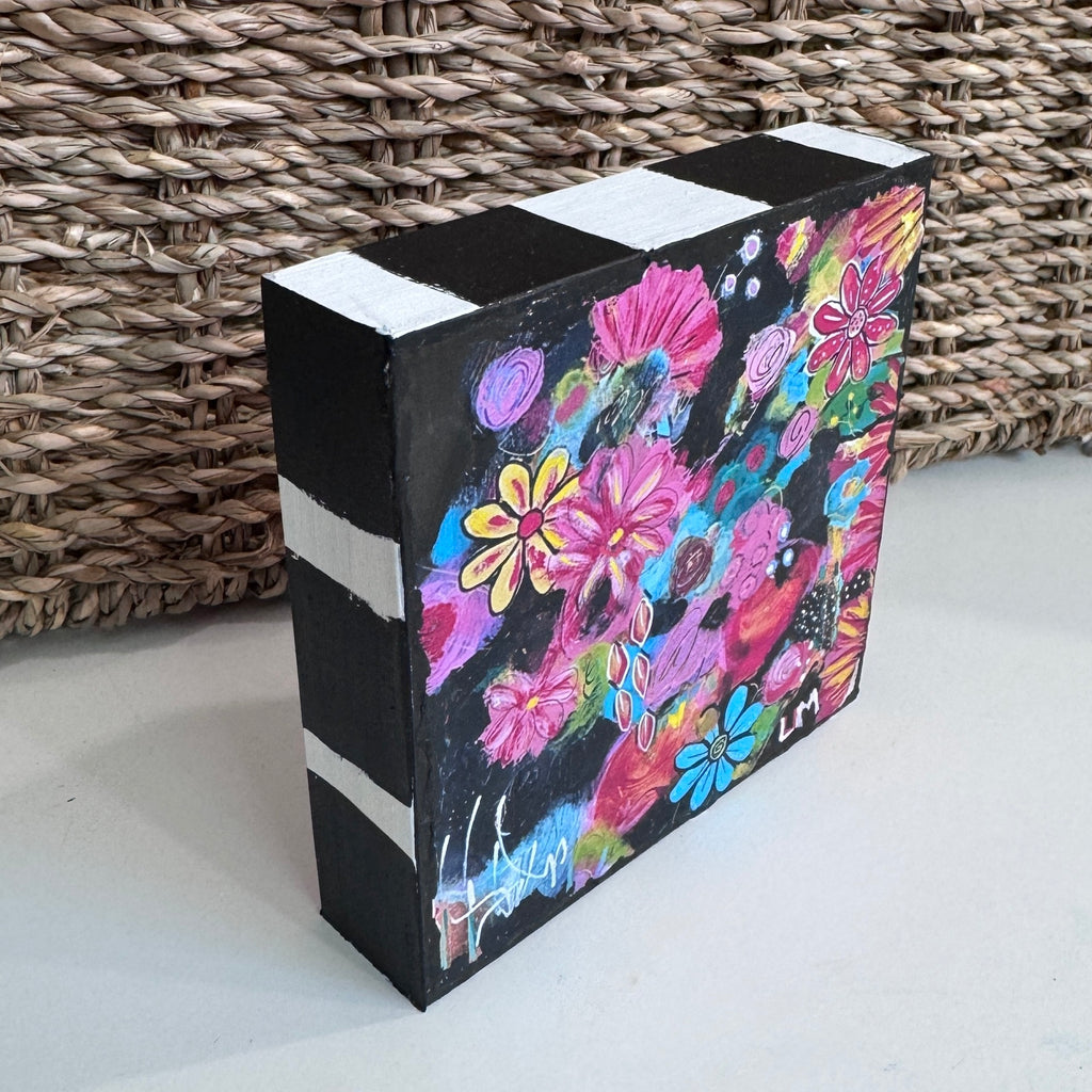 painted wood block standing in front of a basket on a white table