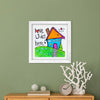 Framed children's drawing of a house with 'Love Lives Here' text on a green wall.