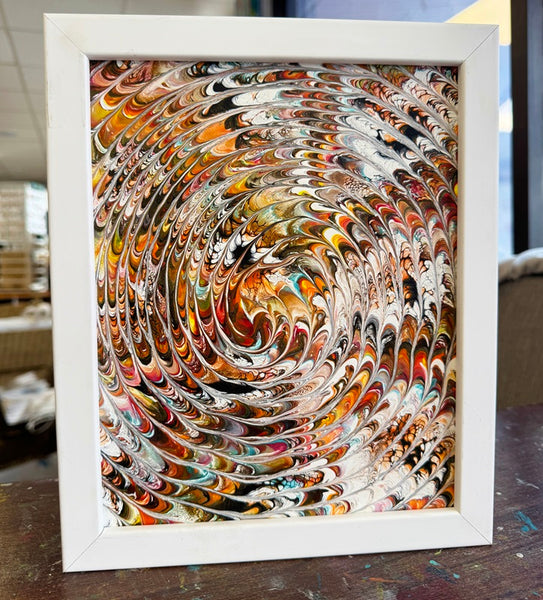 Framed abstract artwork with swirling colors in white frame