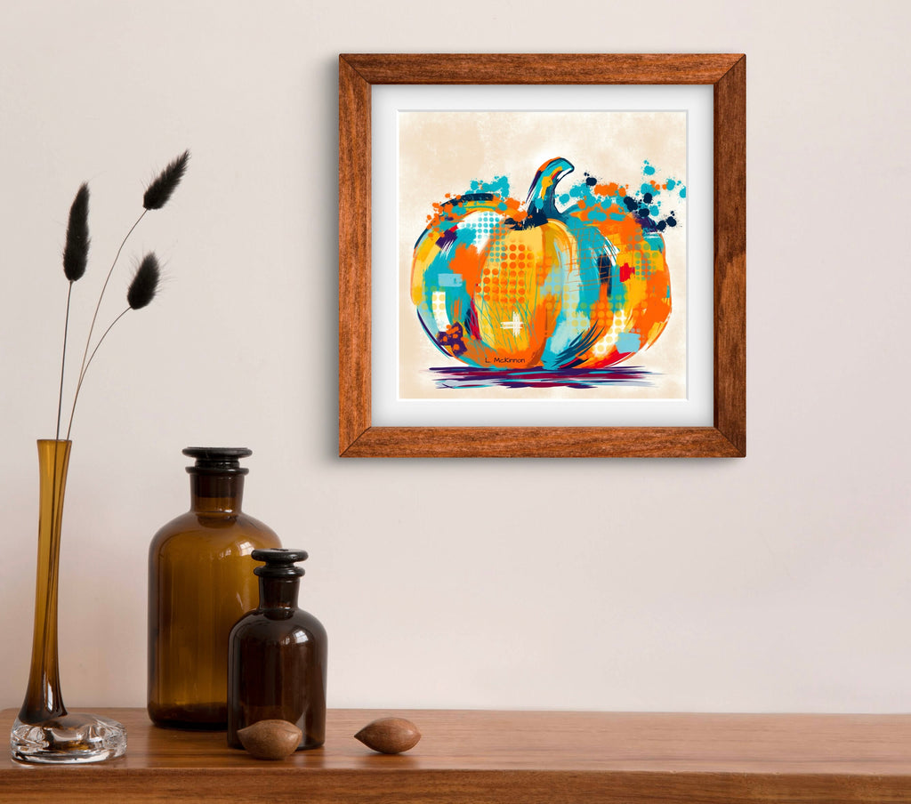 Framed abstract pumpkin painting on a wall above a wooden shelf with decorative items.